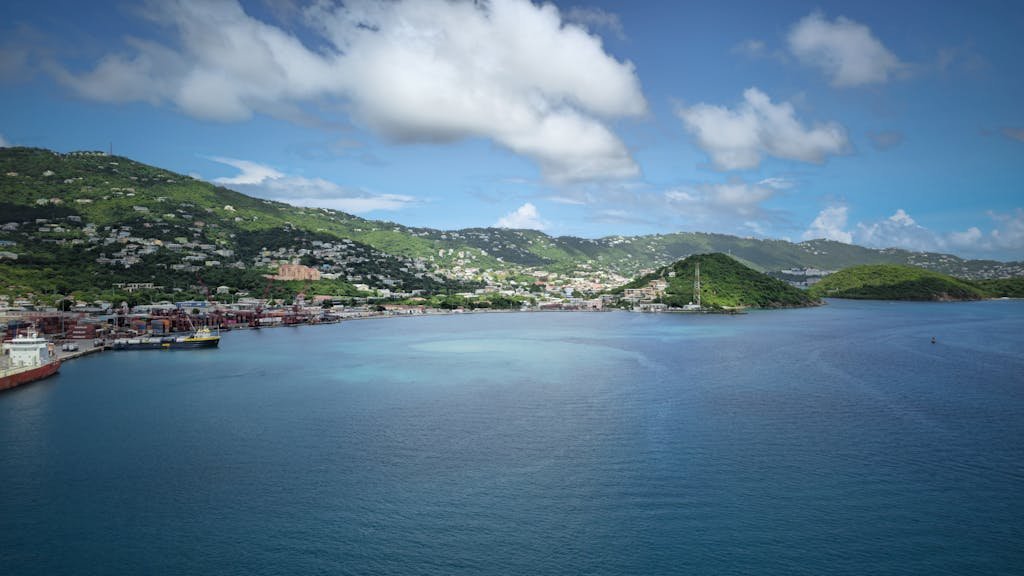 Explore the vibrant and scenic harbor of St. Thomas with lush green hills and clear blue water, perfect for a tropical getaway.