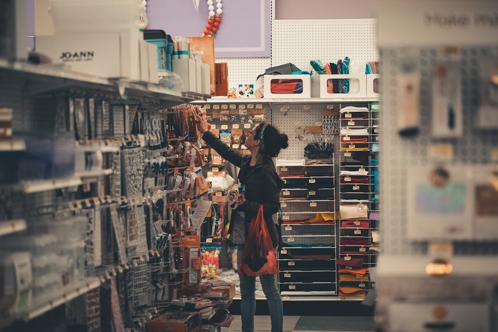 Woman reaching for items in a busy craft store aisle, exploring various art supplies. Shopify SEO Tips